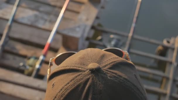 Рибалка дивиться на відстань до водного басейну і чекає, поки риба ловитиме — стокове відео
