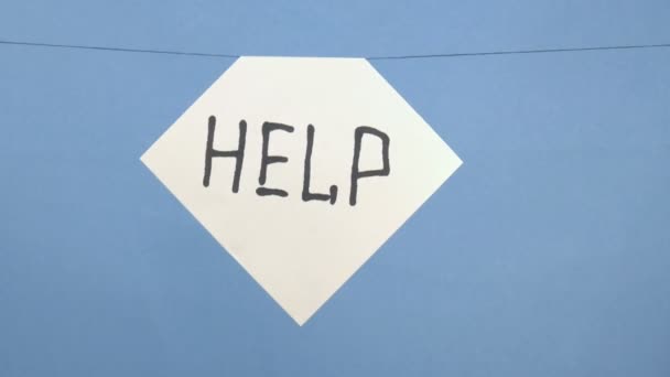 Burning and smoking white sheet of paper with a black inscription "help" on a blue background — Stock Video