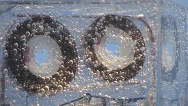 Audio cassette floats in water with bubbles — Stock Video