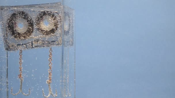 Cassete de áudio flutua na água com bolhas para fundo — Vídeo de Stock