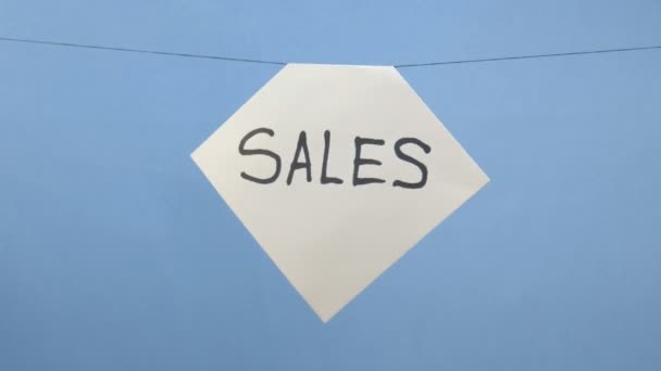 Brennendes und rauchendes weißes Blatt Papier mit schwarzer Aufschrift "Verkauf" auf blauem Hintergrund — Stockvideo