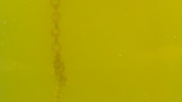 Ljud kassett flyter i gult vatten med bubblor, syra och gift — Stockvideo