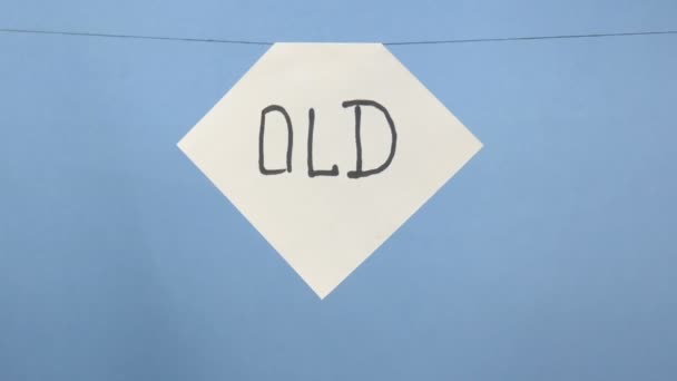 Burning and smoking white sheet of paper with a black inscription "old" on a blue background — Stock Video