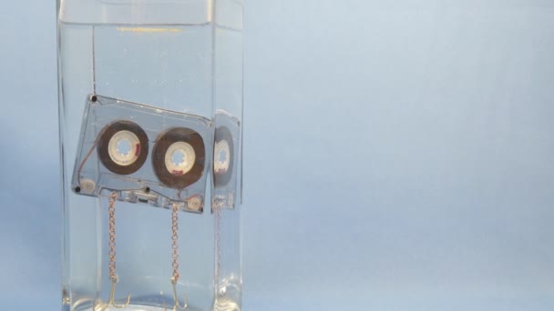 Audio cassette floats in water with bubbles for background — Stock Video