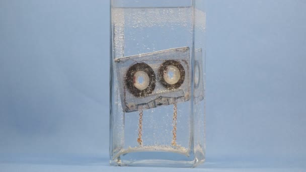 Audio cassette drijft in water met bubbels voor de achtergrond — Stockvideo