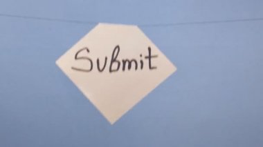 Bir adam mavi arka planda siyah bir yazı olan beyaz bir kağıt asıyor.