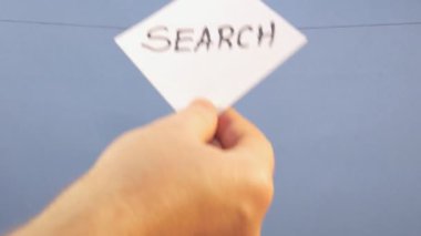 A man hangs a white sheet of paper with a black inscription 