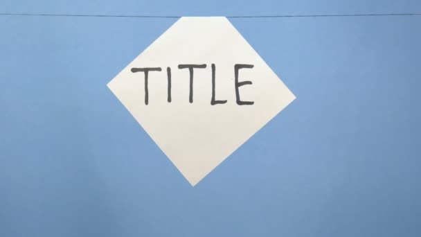 Queimando e fumando folha branca de papel com uma inscrição preta "título" em um fundo azul — Vídeo de Stock