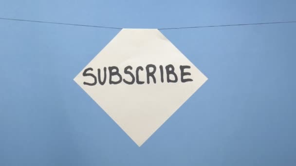 Спалювання і куріння білого аркуша паперу з чорним написом "підписка" на синьому фоні — стокове відео
