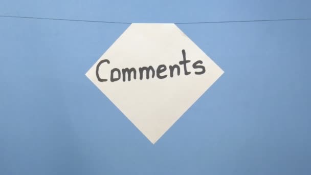 Hoja de papel blanco ardiente y humeante con una inscripción negra "comentarios" sobre un fondo azul — Vídeo de stock