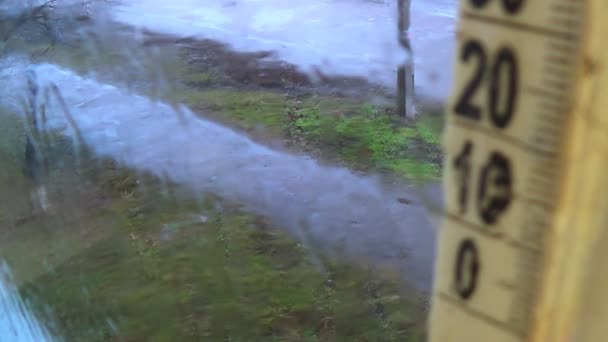 Tempo chuvoso lá fora. Gotas no vidro da janela, escala termômetro nebuloso — Vídeo de Stock