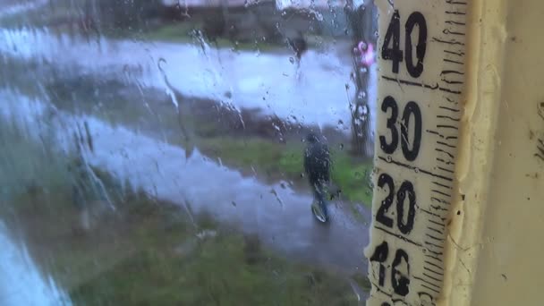 Regenwetter draußen. Tropfen auf der Fensterscheibe, neblige Thermometerskala — Stockvideo