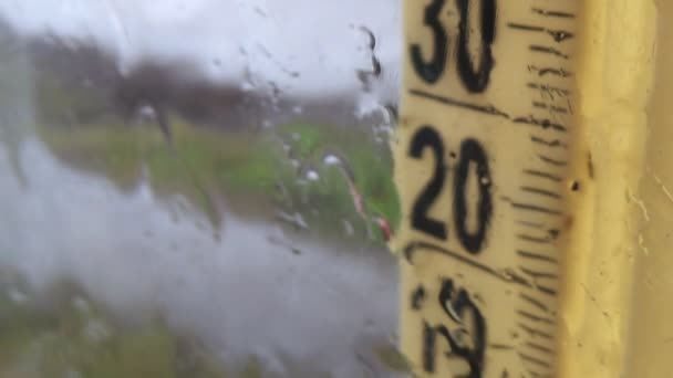 Regenwetter draußen. Tropfen auf der Fensterscheibe, neblige Thermometerskala — Stockvideo