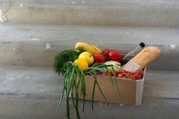 Food delivery at home during the pandemic. Health food. A box of groceries. A box of fresh vegetables. Delivery by volunteers to the pandemic. Safe delivery to the coronavirus.