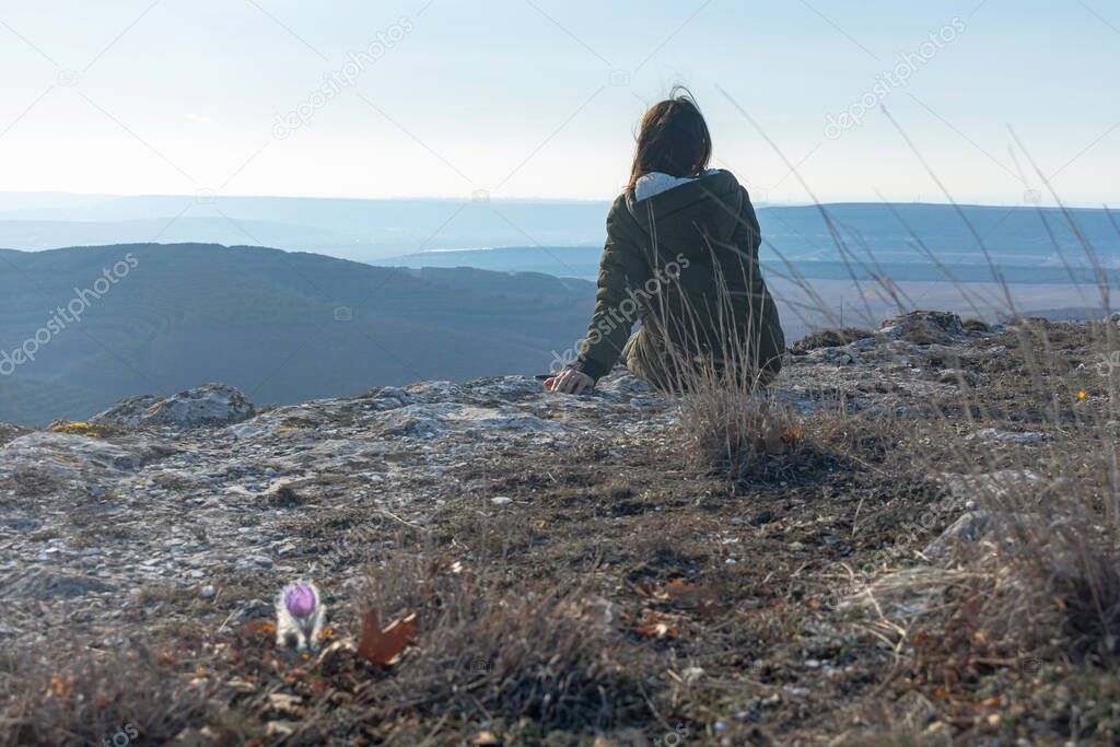 A female traveler drinks tea with a view of the mountain landscape. A girl drinks tea on a cliff in the Crimea. Relax with a beautiful view of the blue distance.