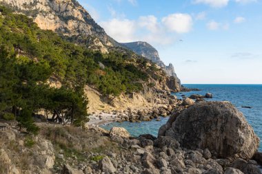 Deniz dalgaları ve muhteşem kayalık sahil manzarası. Sakin turkuaz deniz suyu ve kayaların manzarası. Deniz yüzeyinin ve kayalık sahillerin çizimi. Yarımadanın kayalık kıyıları