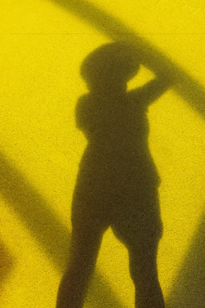 Shadow of the photographer\'s girl on the ground. A girl photographs her reflection in the shadow. Bright yellow background. Concept of travel and art. A girl in shorts and a hat. Girl with a camera.