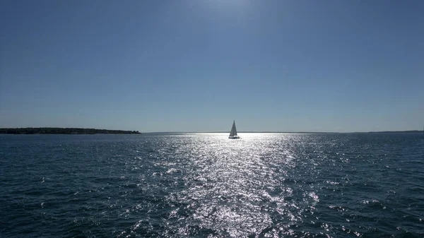 One sail boat in open sea with backlight sun and bright light re — 图库照片