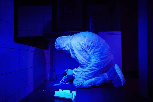 Técnico criminólogo recogiendo ADN en lugar de crimen bajo luz UV — Foto de Stock
