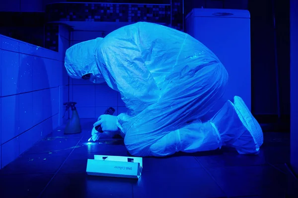 Criminólogo trabajando en el lugar del crimen bajo luz UV para recolectar ADN de manchas de sangre —  Fotos de Stock