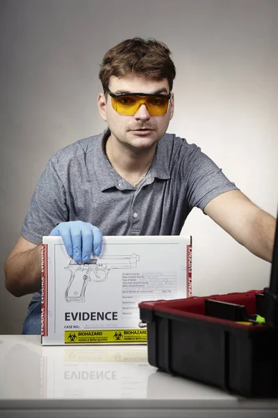 Поліцейський технік на роботі з коробкою вилученого пістолета — стокове фото