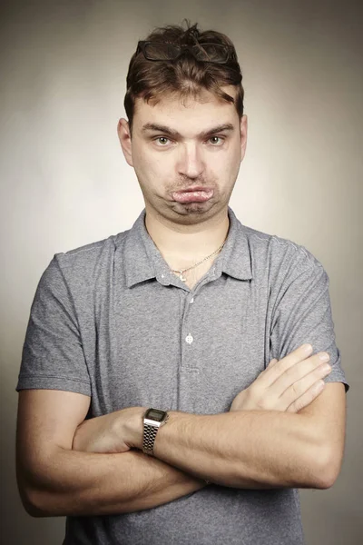 Gek volwassen man in grijs shirt maken gezichten in de studio — Stockfoto