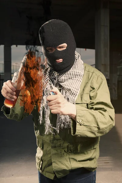 Анархист в балаклаве, зажигающий бутылку с зажигательной смесью — стоковое фото
