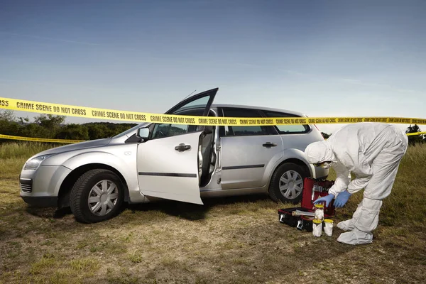 Criminologist technician collecting evidences and traces from around car — Stock Photo, Image