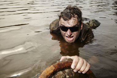 Islak ve kirli nehir üstesinden sonra üniformalı asker