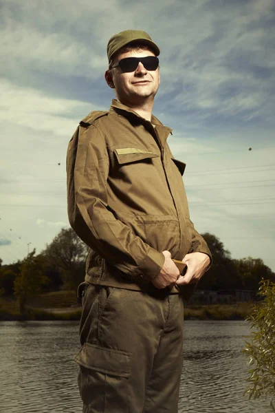 Soldier in uniform and sunglasses posing near river bank — Stock Photo, Image
