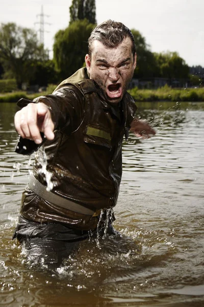 Natte en vuile soldaat in uniform boos in de stroom van de rivier — Stockfoto