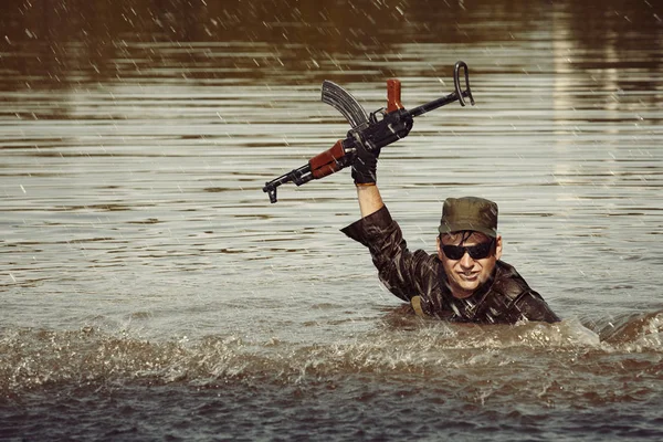 Soldado en uniforme nadando en el lago con rifle de asalto — Foto de Stock