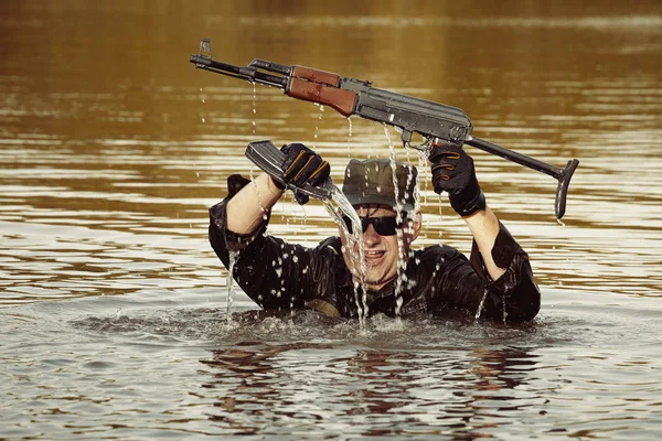 Soldier in uniform swimming in lake with assault rifle — Stock Photo, Image