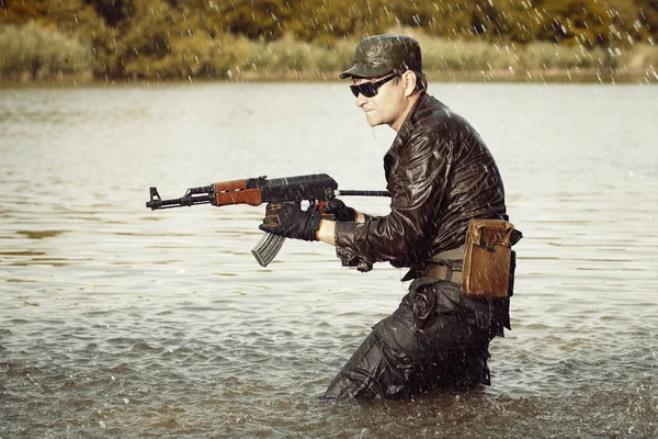 Soldier in uniform attacking from lake with assault rifle — Stock Photo, Image