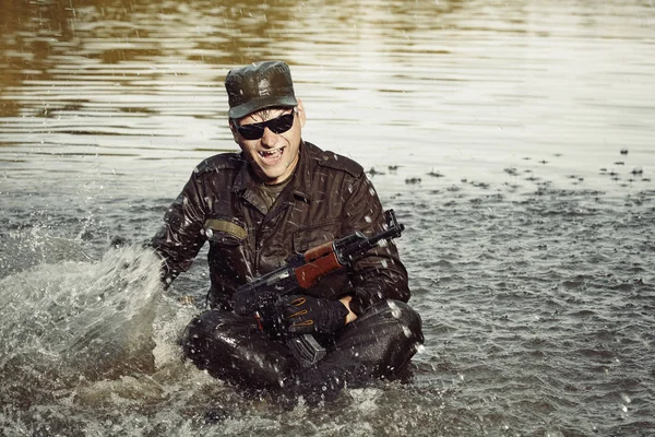 Сумасшедший солдат в форме после купания в озере с автоматом — стоковое фото