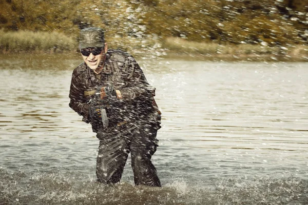 Soldado em uniforme atacando do lago com rifle de assalto — Fotografia de Stock