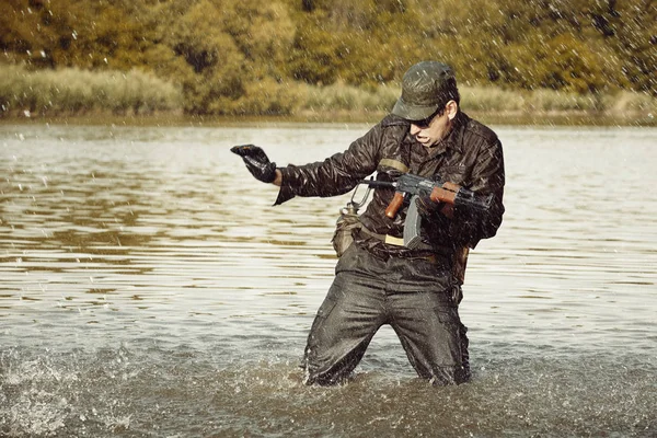 Soldier in uniform attacking from lake with assault rifle — Stock Photo, Image