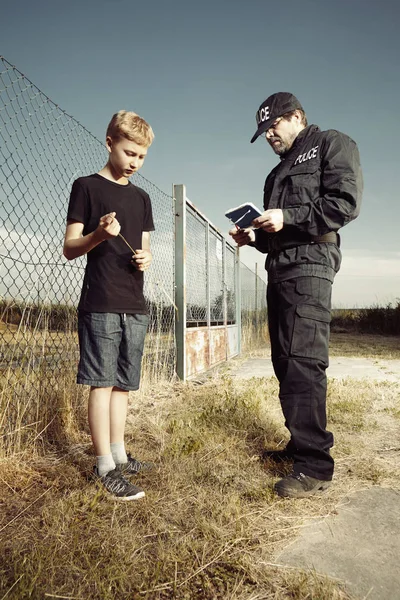 Polisen mannen frågar tonårspojke i fält — Stockfoto