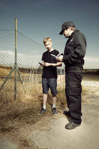 Teenage boy answering to police man in fields