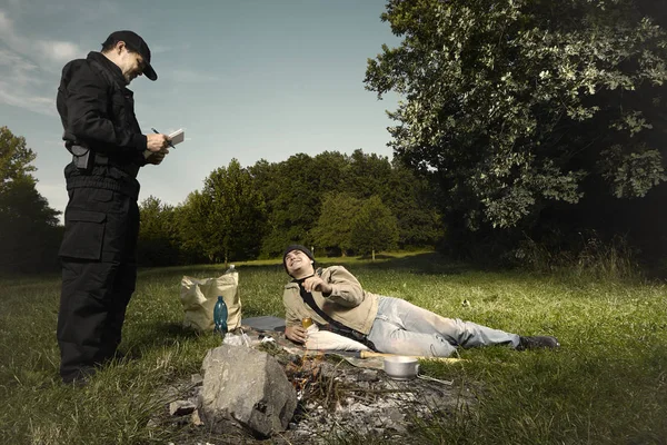 Молодой бродяга пойман в парке полицейским у нелегального камина — стоковое фото