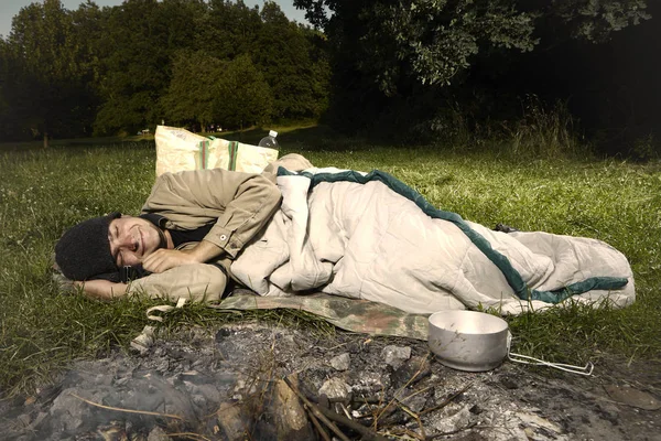 Vagabond young man sleeping in bag in day time park — Stock Photo, Image