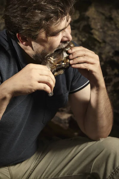 Man relaxing and eating hunted trout in wilderness — Stock Photo, Image