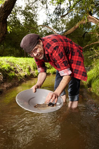 Prospector moderno em estilo hipster panning areia em riacho para ouro — Fotografia de Stock