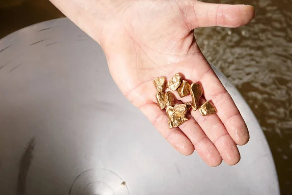 Pepitas de oro que se encuentran en la arena del arroyo por paneo en la mano — Foto de Stock