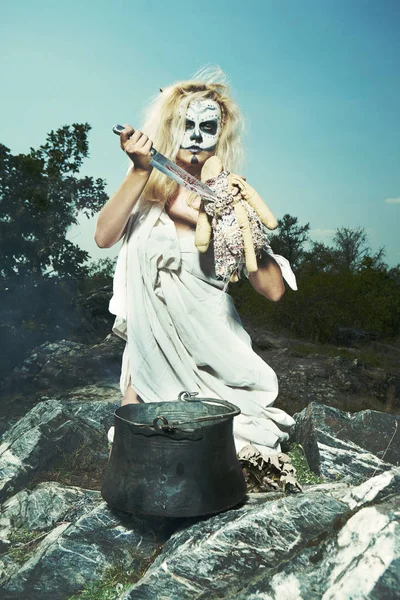 Blonde witch during voodoo ritual spelling some person through fetish doll — Stock Photo, Image