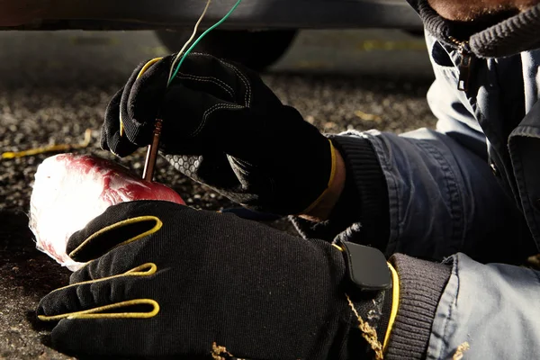 Criminal man placing plastick explosive under car on public — Stock Photo, Image