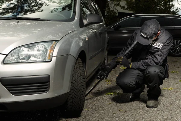 Politie man auto voor mogelijk explosief controleren — Stockfoto