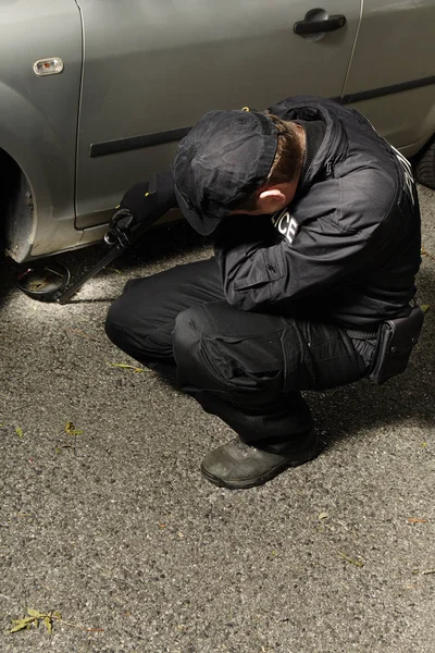 Police man checking car for possible explosive device — Stock Photo, Image