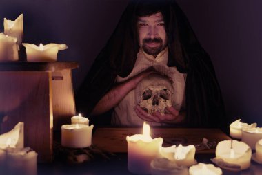 Spiritualist in middle of candles preparing summoning of ghosts clipart