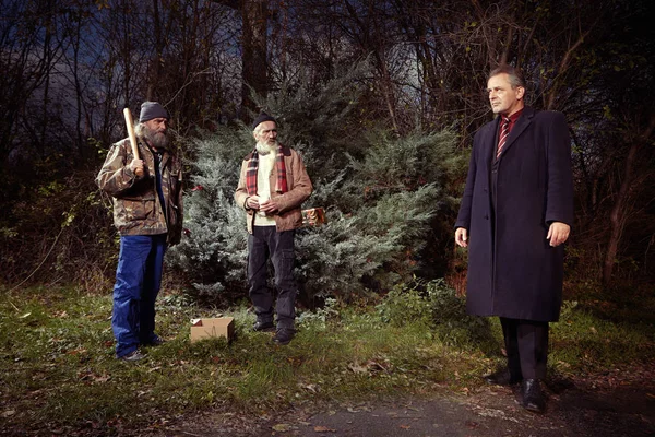 Чоловік у костюмі в парку зустрів пару безпритульних чоловіків — стокове фото